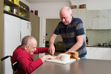Care worker helping man in wheelchair eat